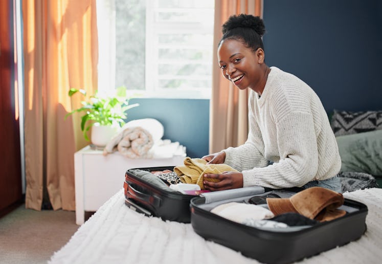A happy woman packs her suitcase for travel booked through Black Friday 2021 travel deals. 