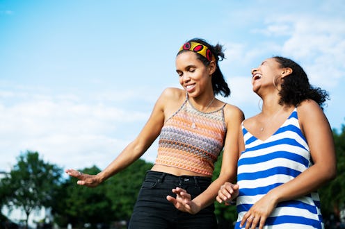 Two women dance and laugh on a sunshiney day. Here's your daily horoscope for November 24, 2021.