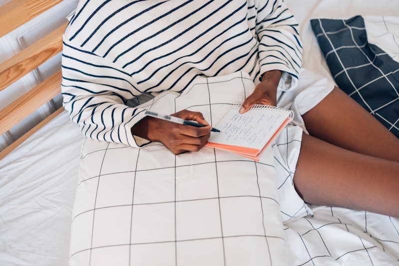 A woman sitting among checked sheets crosses items off a to-do list. Highly productive people share ...