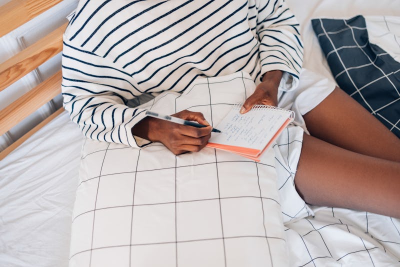 A woman sitting among checked sheets crosses items off a to-do list. Highly productive people share ...