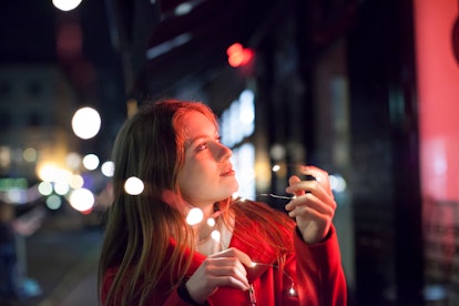 Young woman surrounded by street lights, reading her January 2022 monthly horoscope.