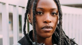 Young woman wearing denim jacket and headphones around neck, thinking about how January 2022 will be...