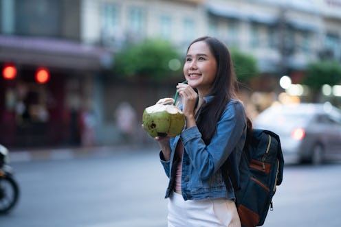 Tourist woman drinking coconut juice while walking in Chinatown ancient civilization