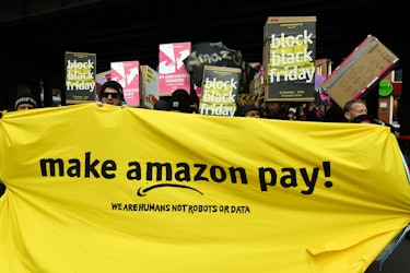 Protesters hold banners and placards during a demonstration to ask the online retailer Amazon to pay...