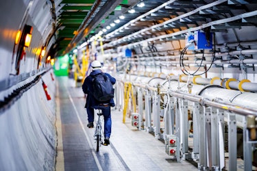 A man rides his bicycle along the beam line of the Large Hadron Collider (LHC) in a tunnel of the Eu...