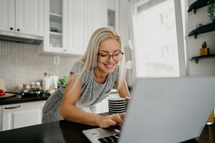 A woman with her coffee does some Cyber Monday shopping from her laptop and posts on Instagram with ...