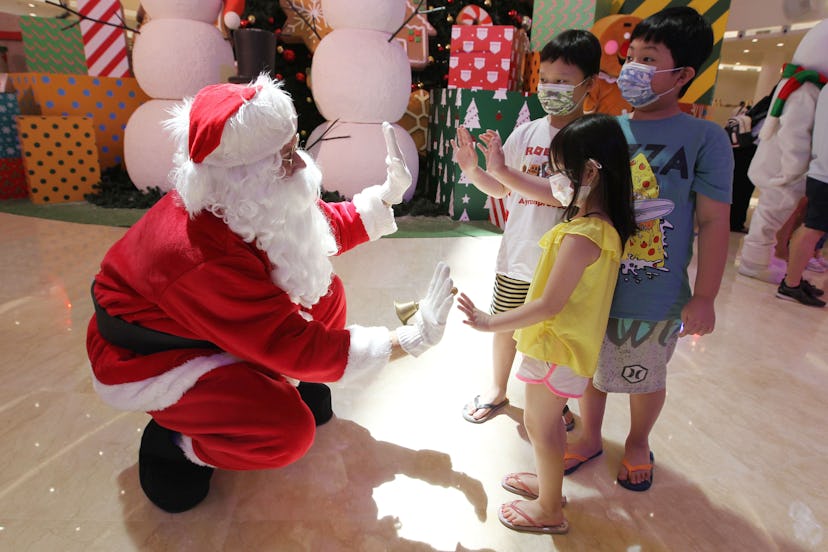 A man dressed as Santa Claus greets children at a shopping mall in Jakarta on December 25, 2020. (Ph...