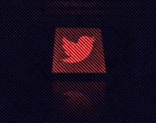Twitter logo displayed on a phone screen is seen with binary code displayed on a laptop screen in th...