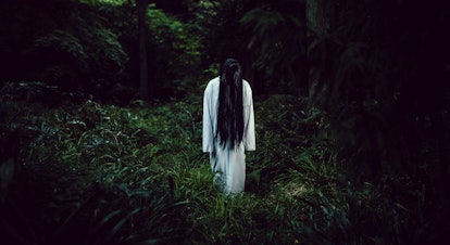 A creepy long black hair Japanese ghost woman in a dark forest.