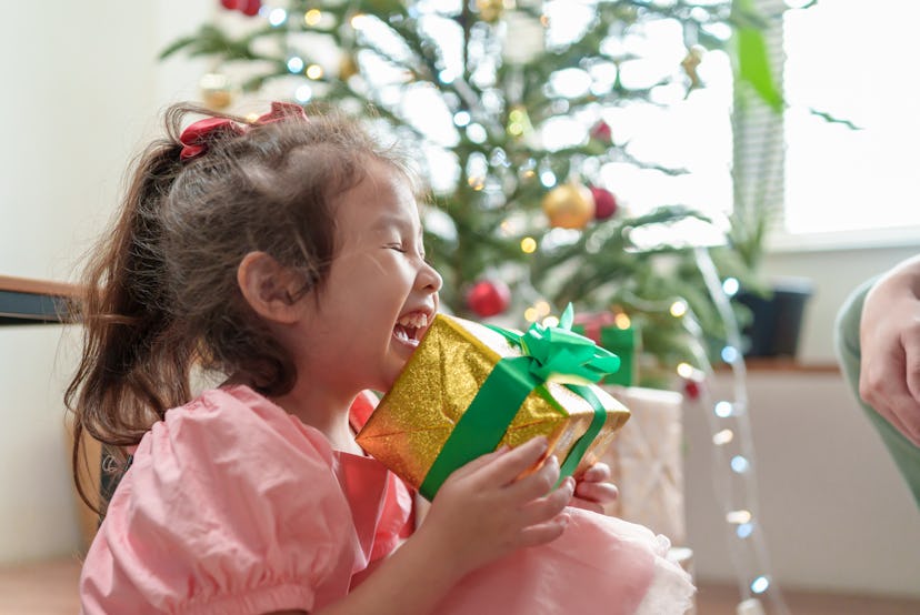 Portrait of little cute girl laughing and enjoying with Christmas present while sitting sitting on t...