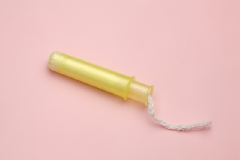 Tampon, yellow applicator, light pink background