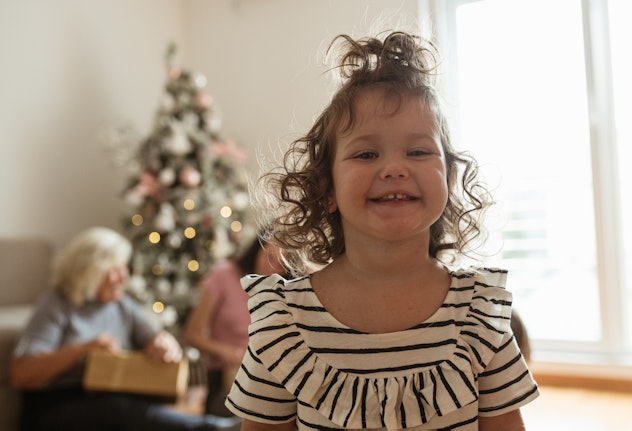 One little girl is standing in the center of the living room.  She is smiling and enjoying during th...