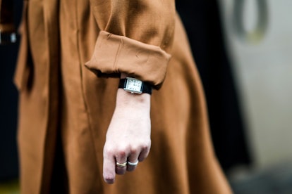 A guest wears a brown suede belted trench coat, a black leather watch, a tri-gold Trinity ring from ...