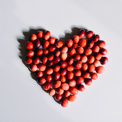 Group of cranberries in a heart shaped disposition on a white background. Copy Space.