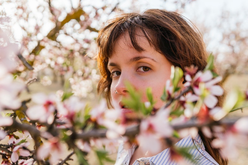 A scorpio woman looks at the camera through cherry blossoms. An astrologer explains scorpio's bigges...