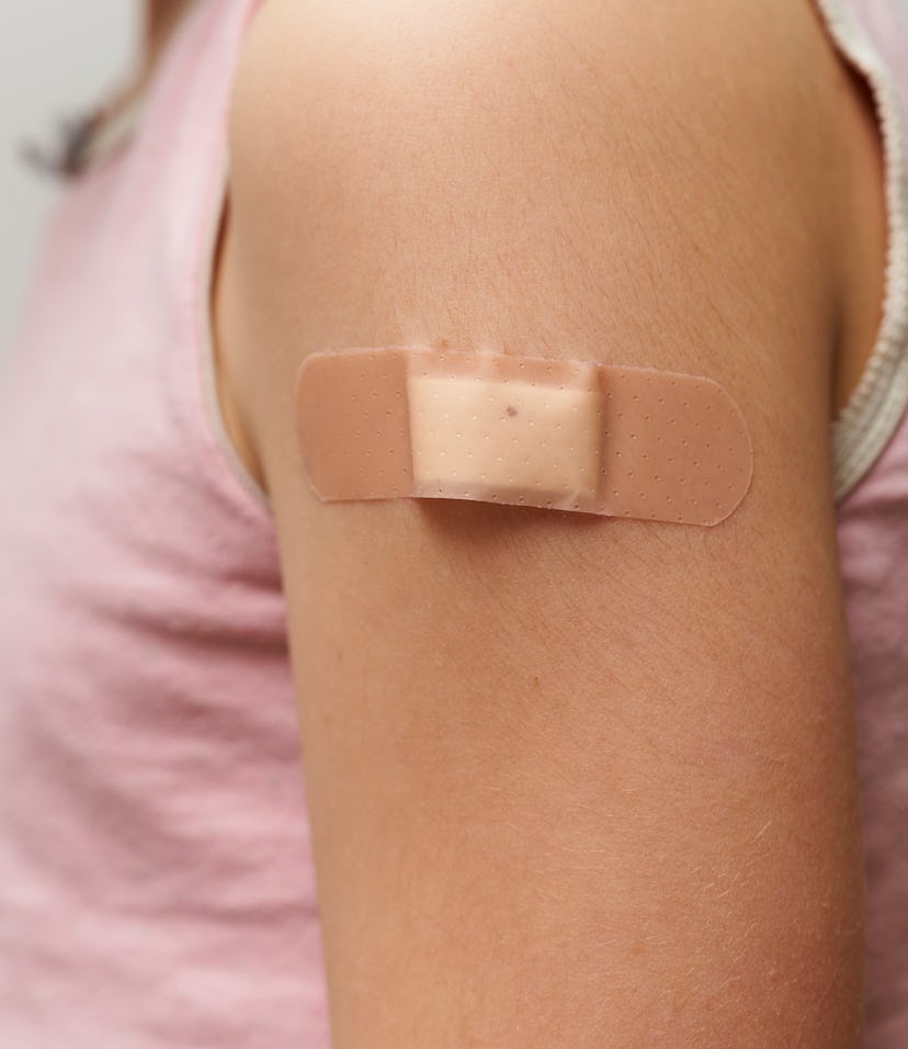 Close up of band aid, on the arm of a caucasian girl after giving her the vaccine