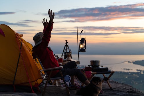 A woman eats dinner while camping at dusk. Here's how the december 2021 new moon solar eclipse will ...