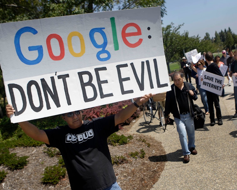 David Ledesma (left) of San Jose holds a sign as he walks with others who gathered to protest Google...