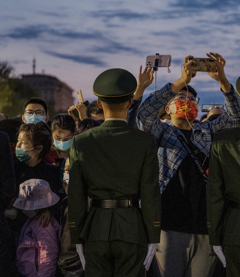 BEIJING, CHINA - OCTOBER 01:A man takes photos as police officers perform crowd control duty before ...