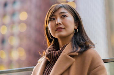 Young woman wearing a coat at night in downtown district the week of December 20, 2021, which will b...