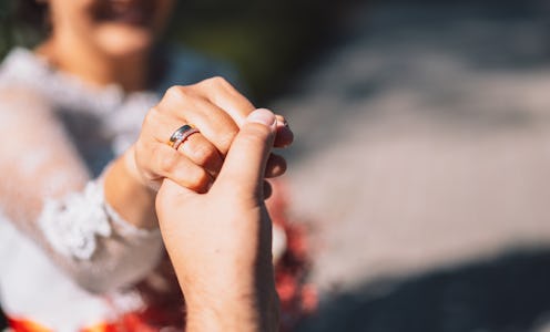 Bride in white dress holding her husband's hand.