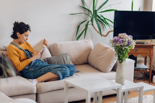 Young woman reading a book and relaxing at home.