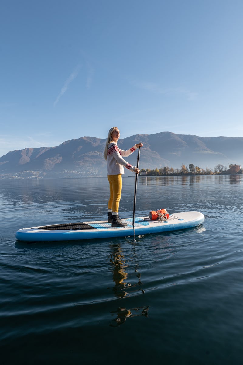 A woman paddleboards on a winter lake. Here's the spiritual meaning of december's new moon.