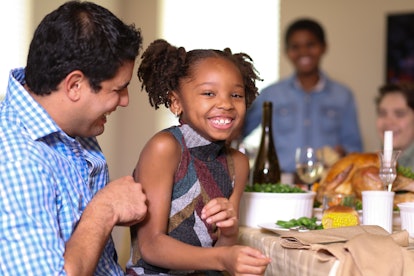 Multi-ethnic family members enjoy eating Thanksgiving or Christmas dinner.  Hispanic, African and Ca...