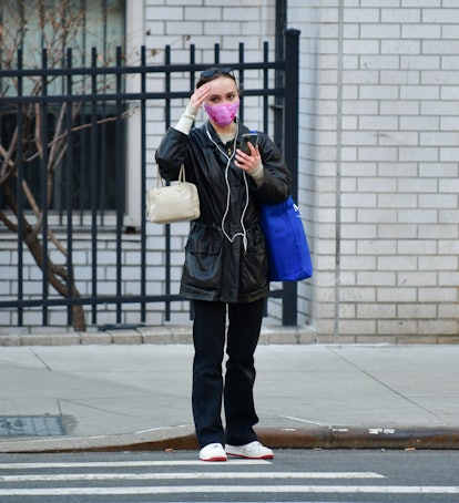Lily-Rose Depp wearing wired headphones on the streets of New York.