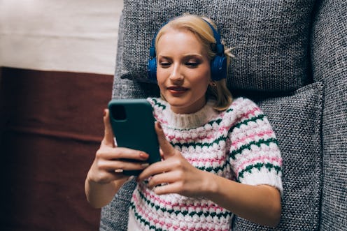 A woman wearing a silly sweater tips creators on TikTok while lying on a couch.