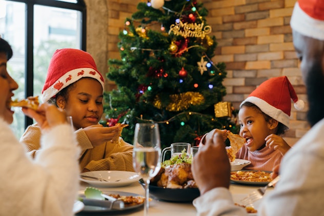 Beautiful young African American family of mother, father and two daughters wearing santa hat enjoyi...