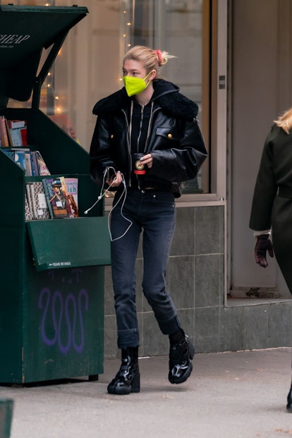 Hunter Schafer wearing wired headphones with a neon green mask.