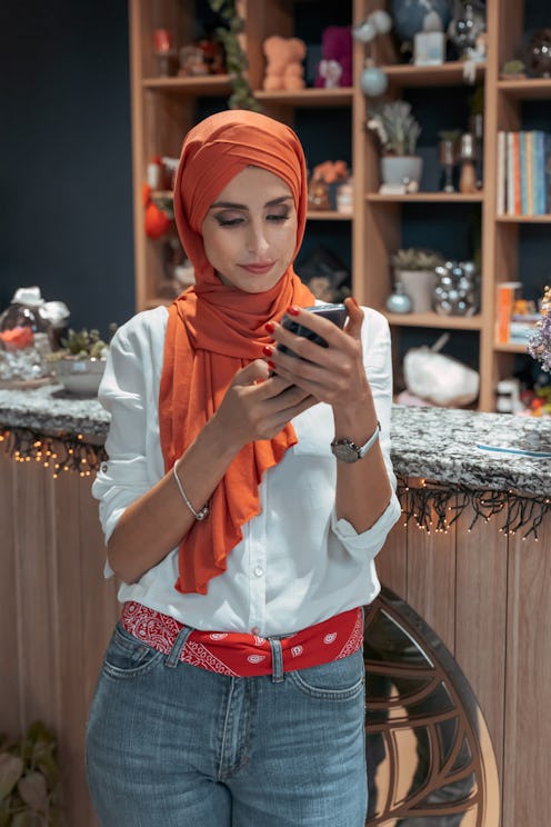 A woman wearing hijab uses a productivity app on her phone. Habit Tracker and Notion are two highly ...