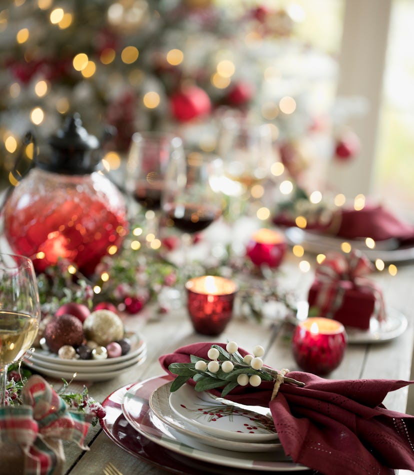 Image of a festive dining table set with small votive candles and string lights.