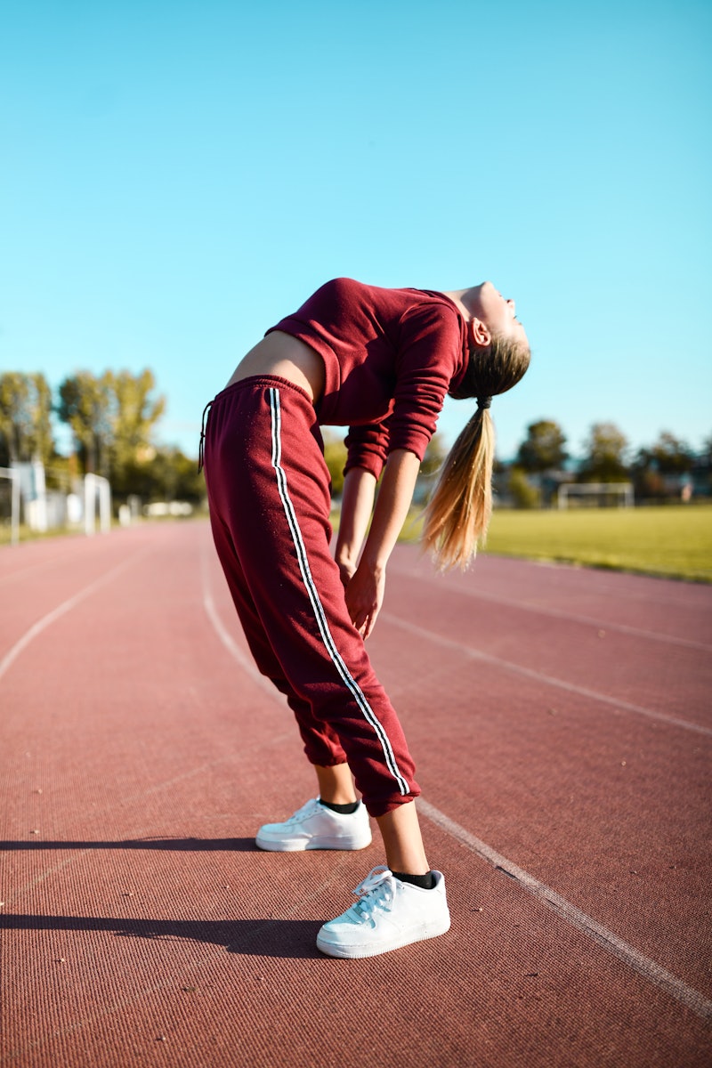 A woman in a tracksuit stretches before running. Here's your horoscope for November 9, 2021.