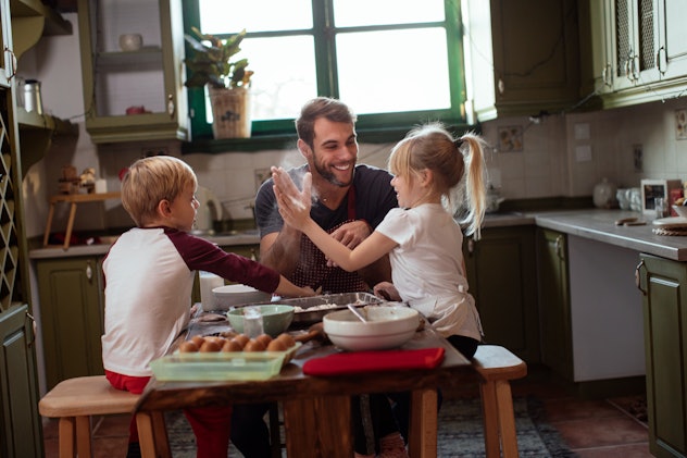 Handsome young father baking Christmas cookies with his son and daughter, telling a christmas dad jo...