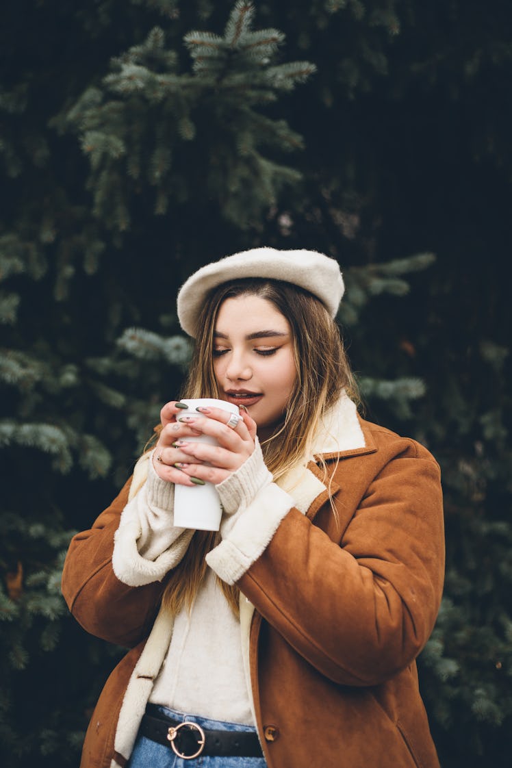 Young woman with closed eyes enjoying her coffee outside as she reflects on which sign will be the l...