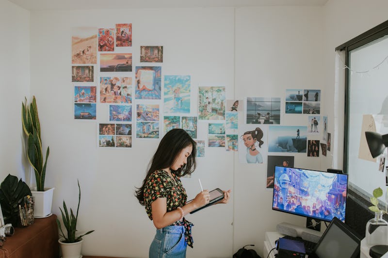 Young creative cartoonist is preparing her portfolio presentation and sketching her work in a digita...