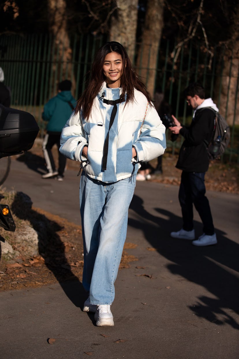 MILAN, ITALY - FEBRUARY 23: Model Hoyeon Jung wears a blue and white jacket, blue jeans, and white s...