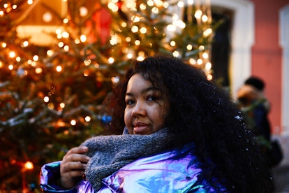 Outdoors winter portrait of young happy mixed race woman with long curly black hair visiting Christm...