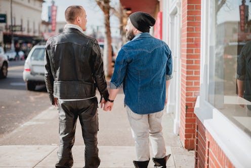 Two mature mixed race gay men window shopping in the city together.