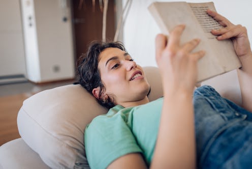 Young woman reading a book and relaxing at home.