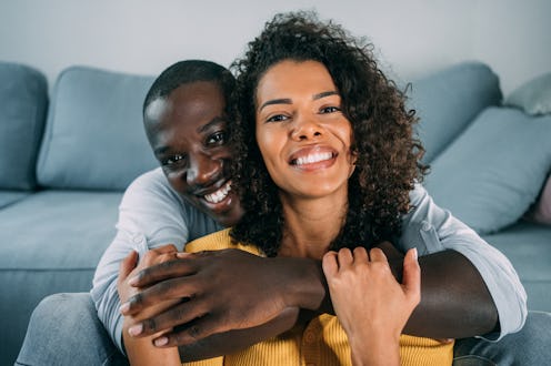 Shot of a cheerful young man hugging his girlfriend on the sofa at home.