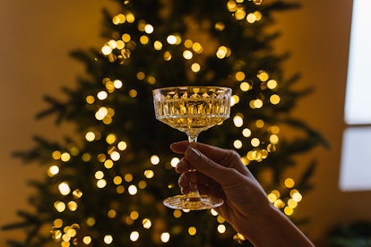 Woman's hand with a glass of champagne on the background of a Christmas tree. Happy New Year concept...