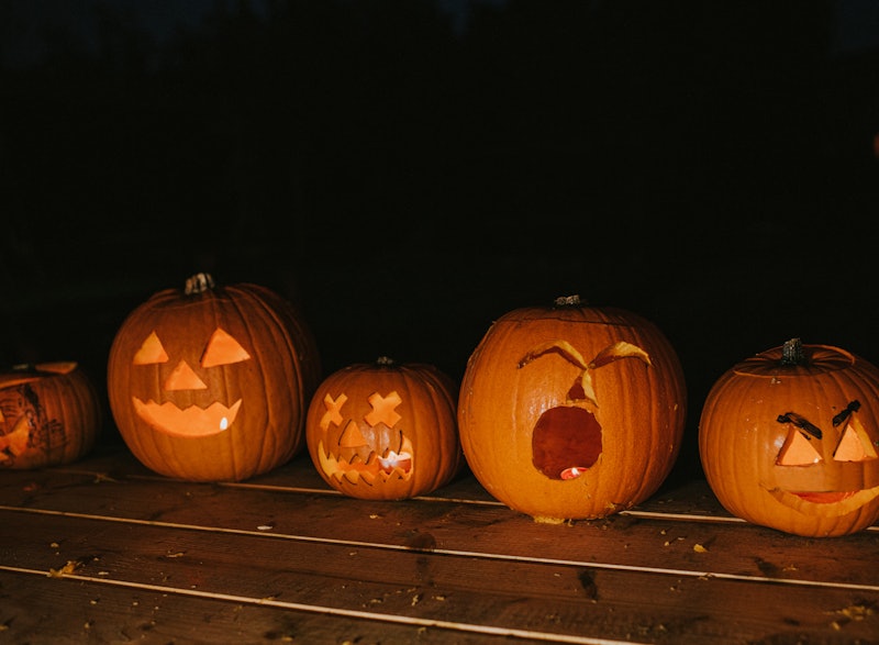 A line up of ripe orange pumpkins, scooped out and carved as a hallowe'en decoration, traditional in...
