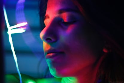 Young woman in neon lights before reading her December 20, 2021 weekly horoscope for her zodiac sign...