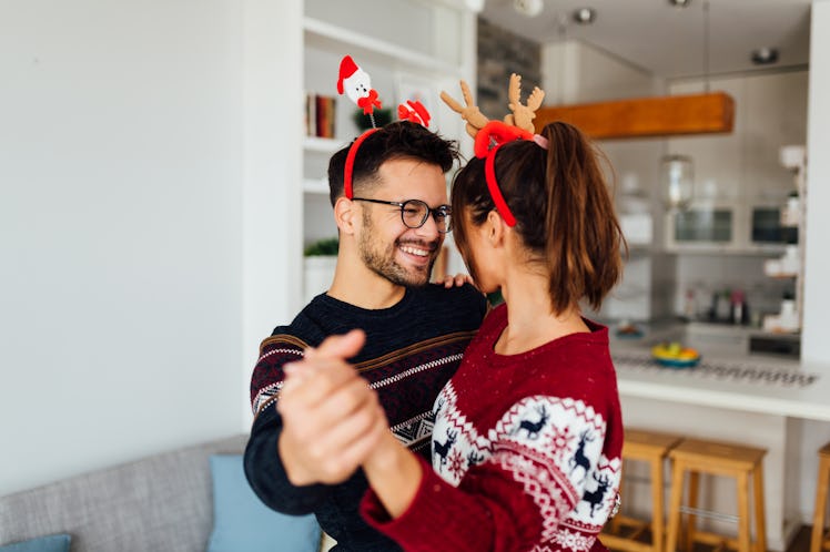 Cheerful young couple dancing together listening to the best Christmas lyrics, which they'll use as ...