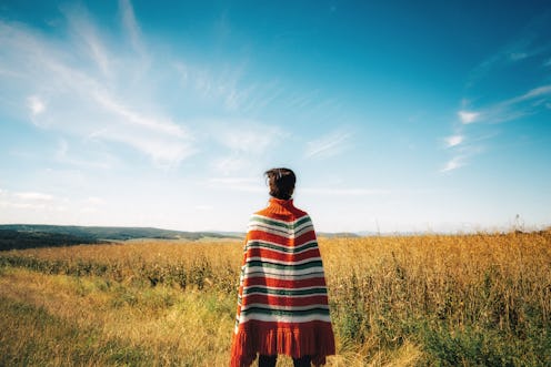 woman with poncho looking over the landscape at sunset hour