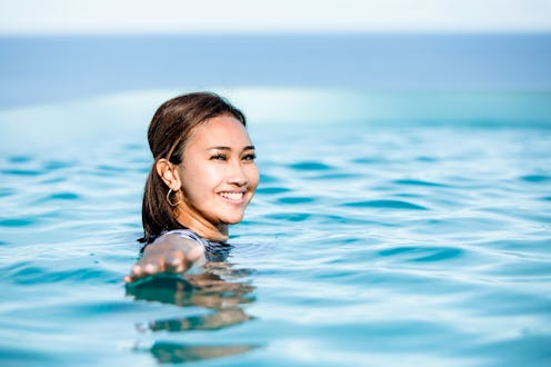 front view of Asian young woman swim in pool looking boats at a sea