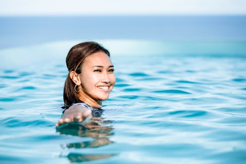 front view of Asian young woman swim in pool looking boats at  a sea